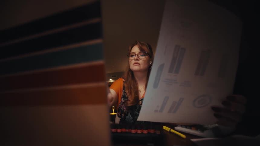 Woman sitting analyzing a paper with graphs