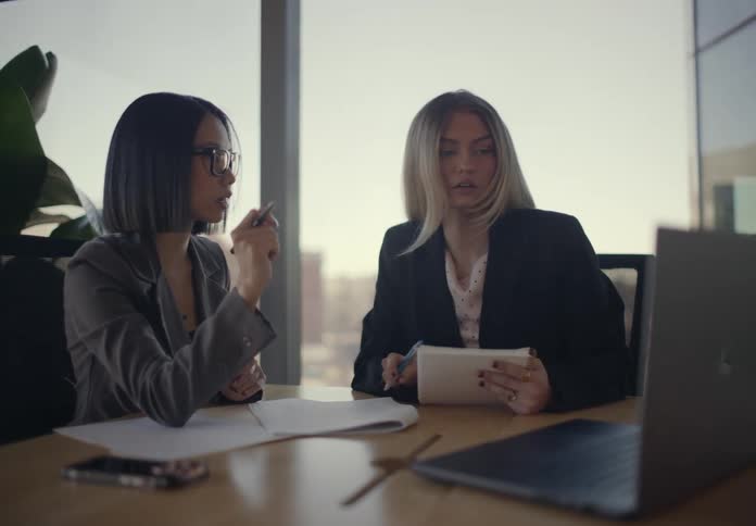 Two women talk at a desk