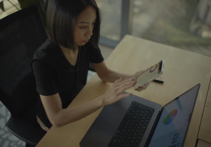 A woman using a smartphone and laptop