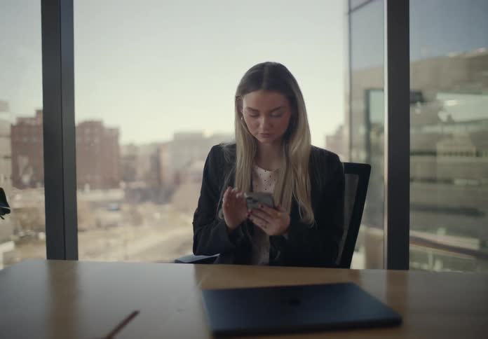 A woman using a smart phone at a desk