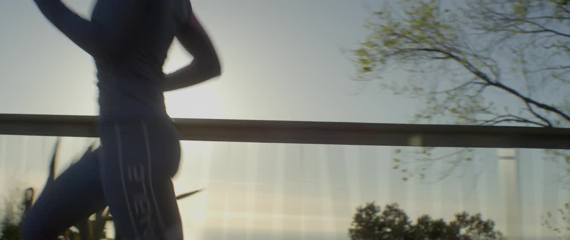 A woman jogs on an outdoor path on a sunny day