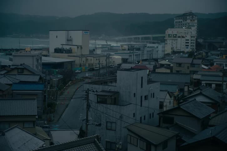 Urban view with residential streets compact buildings and a coastal area in the background under a cloudy sky