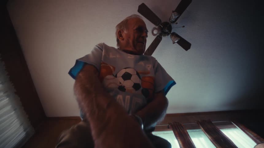 Man standing in his living room holding a golf club as he putts a ball and cheers