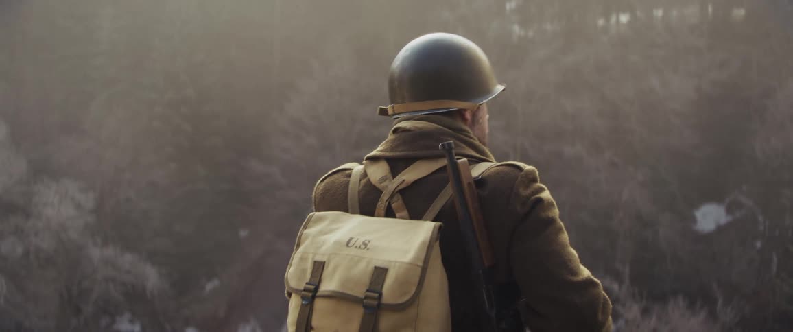 The soldier puts on his helmet in the forest