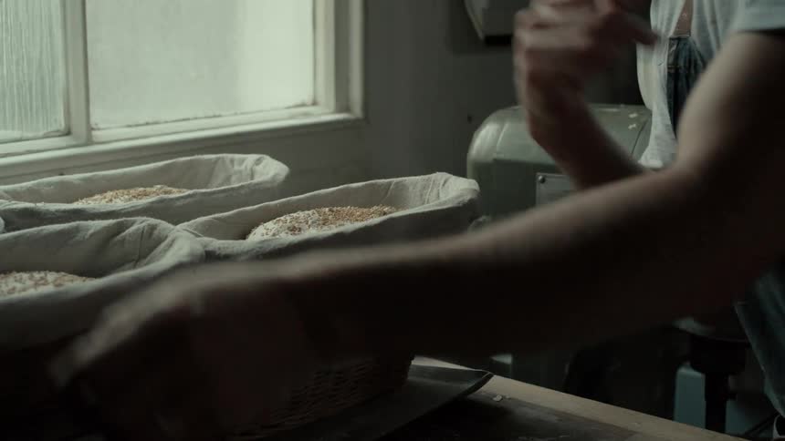 Hand scattering seeds while preparing bread dough