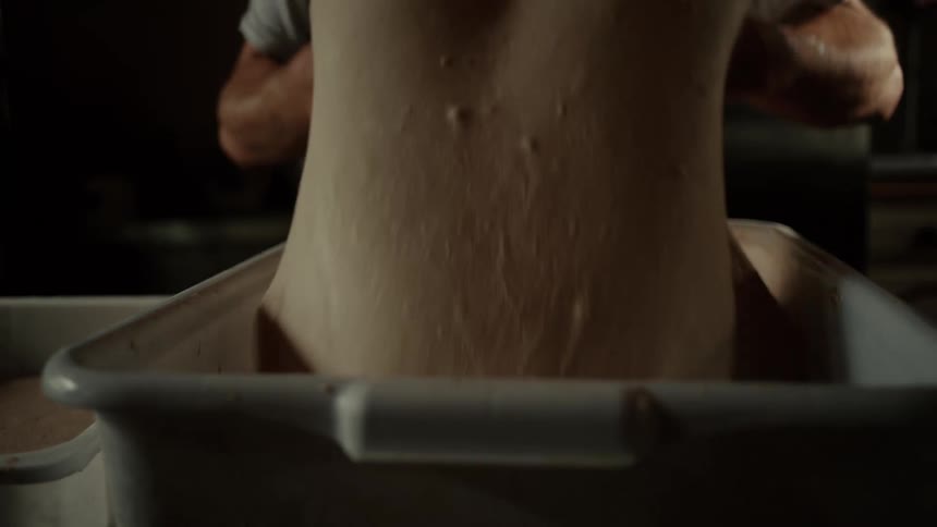 A man throwing dough in a box