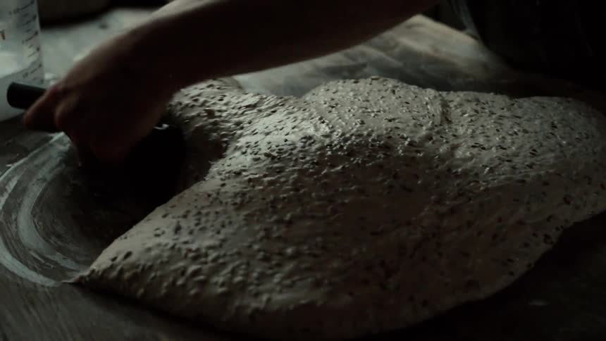 Baker cuts and shapes bread dough on a table