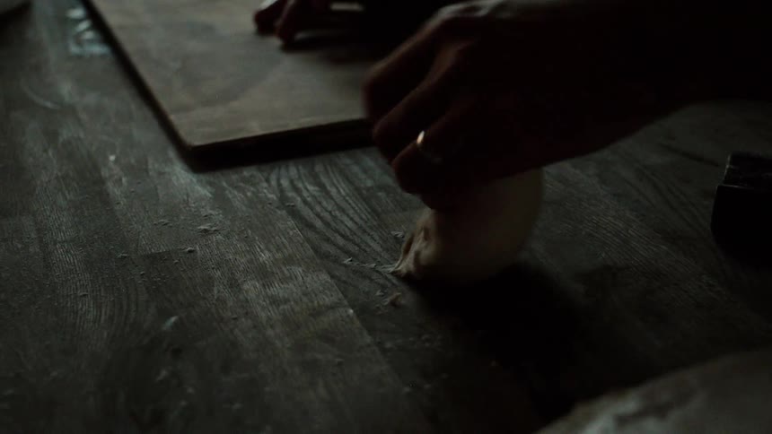A person rolling some dough on a wood board