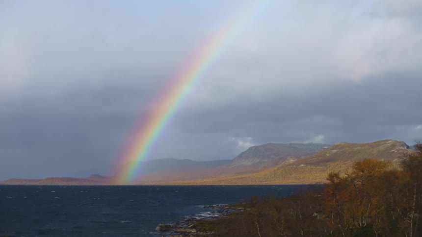 A large rainbow is over the shore