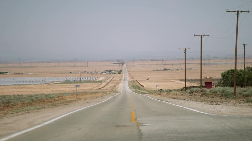 Power lines stand erect next to a desert road