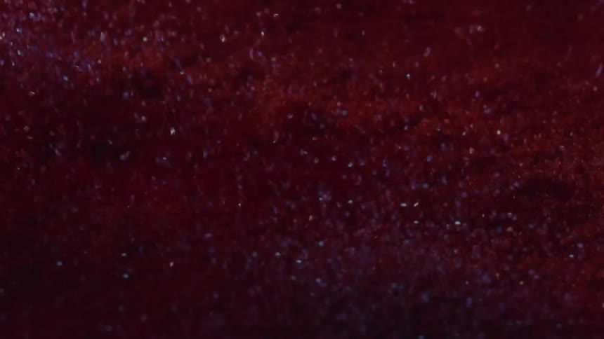 An extreme closeup of a abstract red textured surface with fine particles and subtle sparkling details