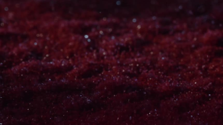 Dispersed red pigment creates a dense surface with evenly distributed shimmering particles