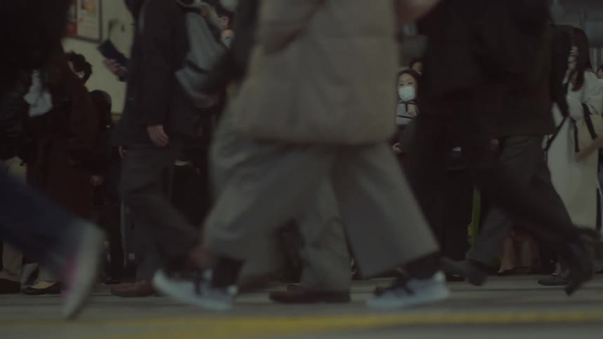 People wearing face masks and winter outerwear walk through a busy terminal
