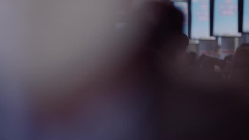 Large group of people walking in a hallway with digital monitors changing images on the walls