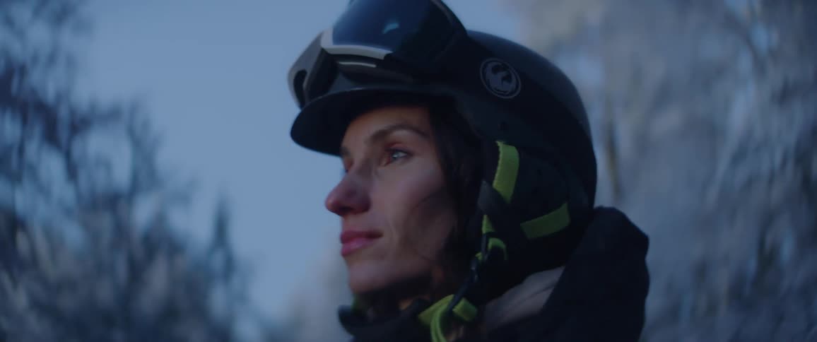 Woman wearing a helmet stands outdoors in a frost covered forest on a winter day