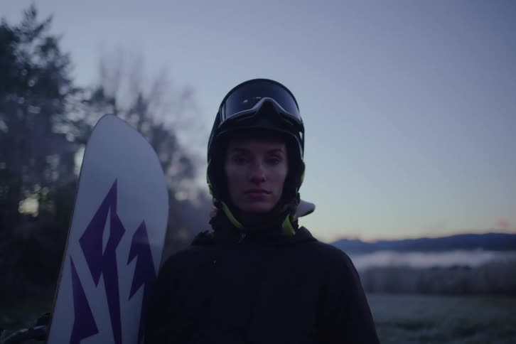 Woman wearing a helmet stands with his snowboard