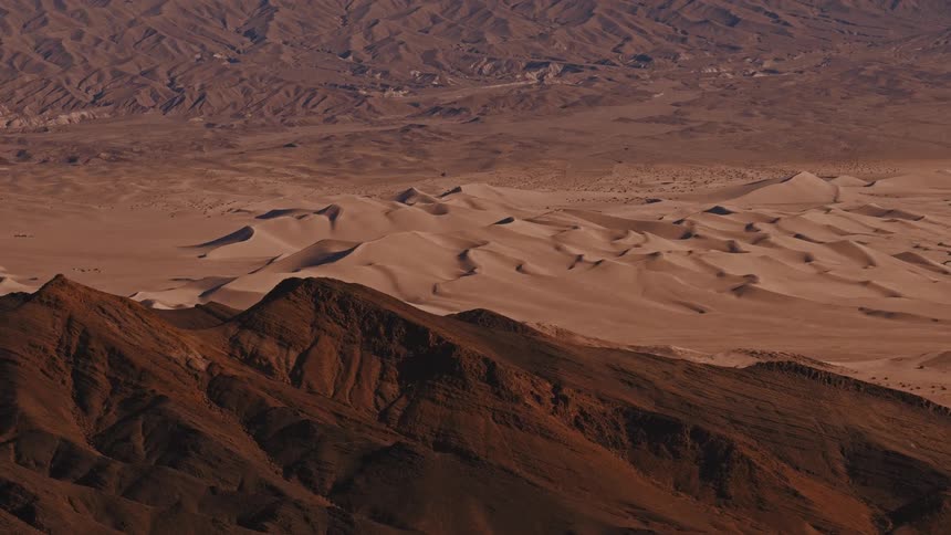 View from over a mountain of dunes across the desert