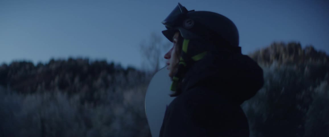 A woman standing outdoors with a snowboard