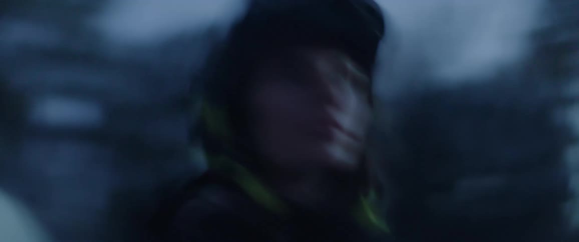 A softly blurred dreamlike closeup shows a snowboarder in a helmet and goggles emerging against a cold blue backdrop