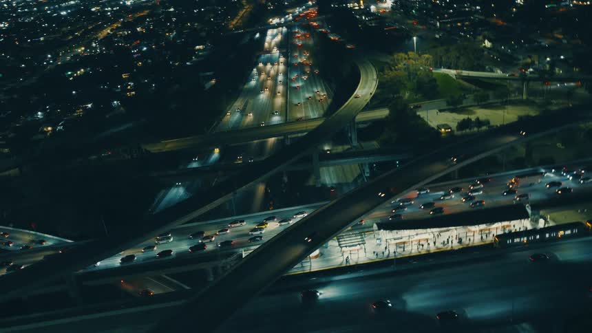Traffic moves on the highways as lights on city buildings glow in the darkness