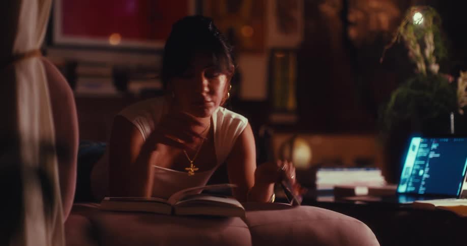 Woman lying down interacting with a smartphone and reading a book