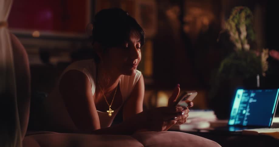 Woman lying in the living room using a smartphone