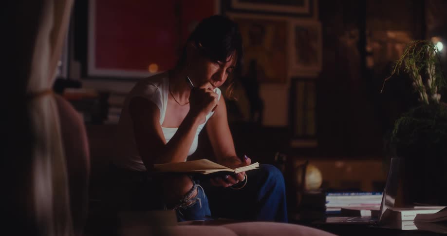 A woman writing in a notebook in a room