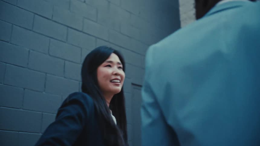 Two business professionals engaged in a conversation while walking along an urban street