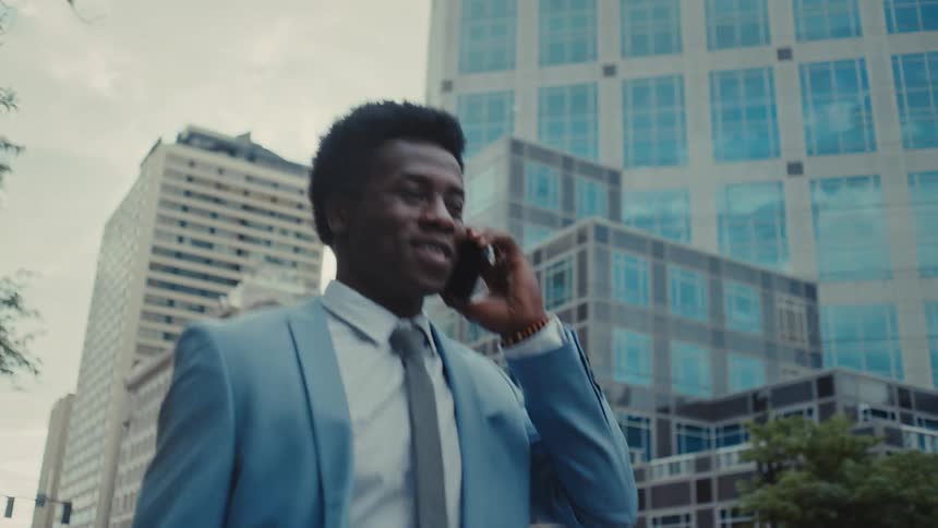 Man in blue suit walking and talking on a call