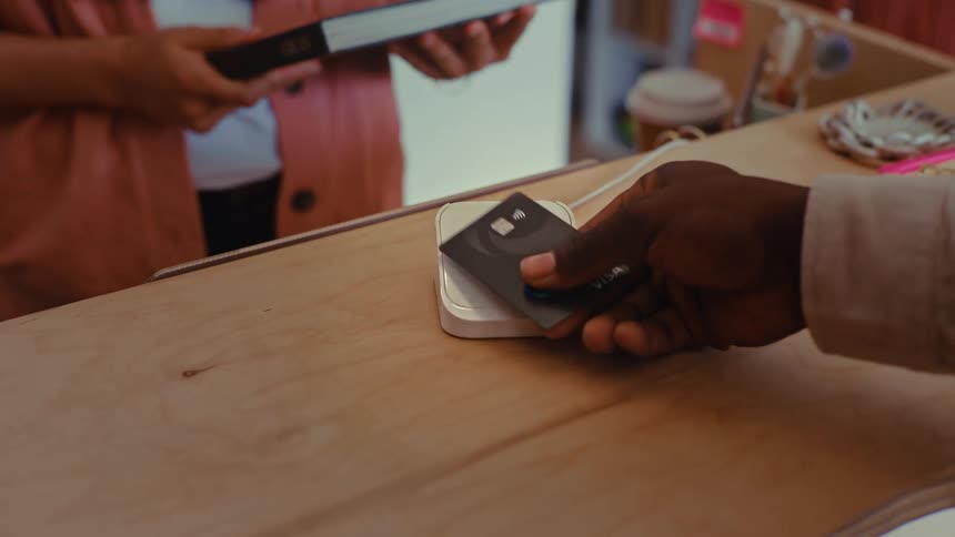 Contactless payment is made with a card over a terminal on a shop counter