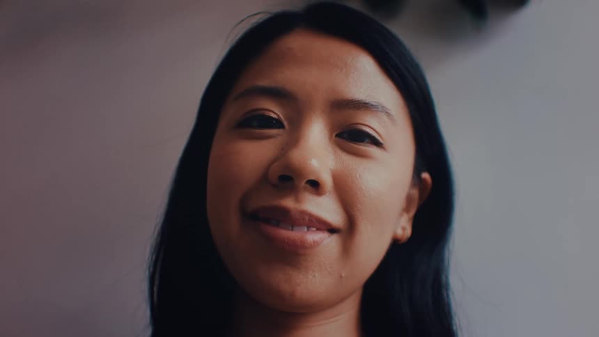 Woman smiles in an indoor setting with a blurred background