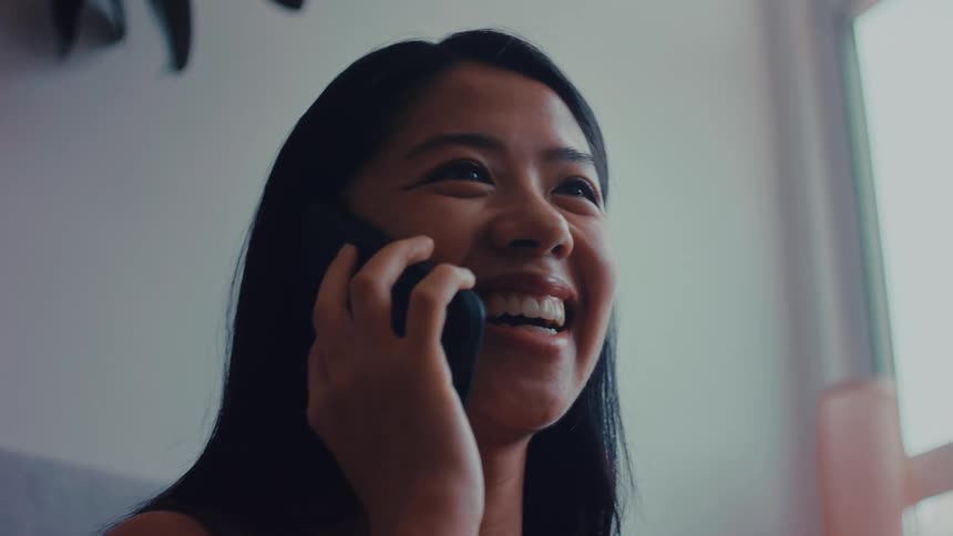 Teenage girl laughs as she talks on her phone