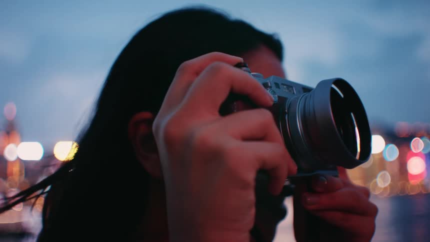 A woman taking a photo outdoors at dusk