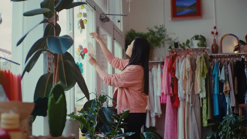 The woman hangs a decoration on the boutique window