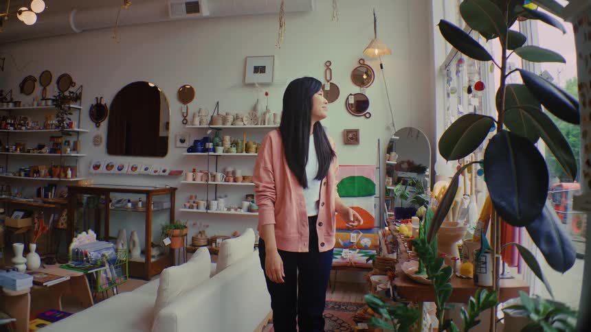 Asian young adult female looking around the decor of a living room and smiling indoors during day time