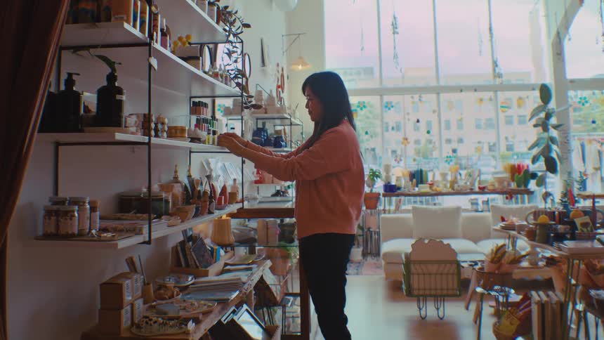 The worker in the shop straightens the items on the shelves