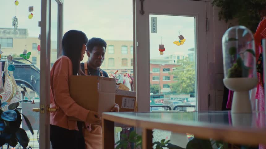 Two workers bring boxes into the boutique