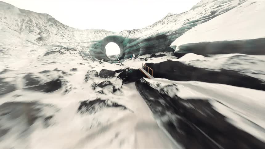 Deep crevasses cut through the surface of a glacier covered by snow and compact ice