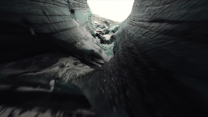 Glacier crevasses reveal layers of blue ice and snow with exposed dark rock areas