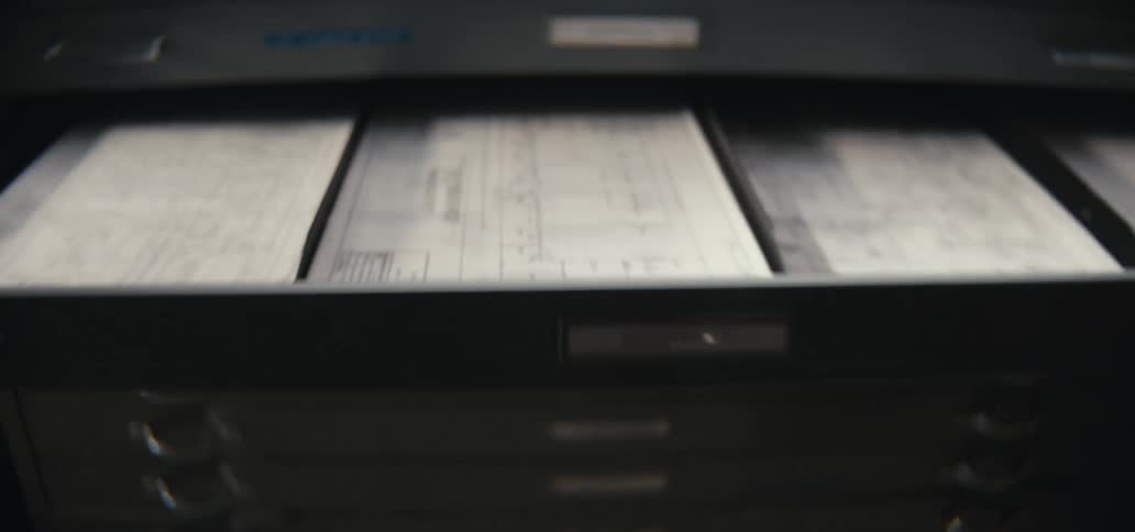 A person pulls open a drawer of a large metal flat file cabinet in an office
