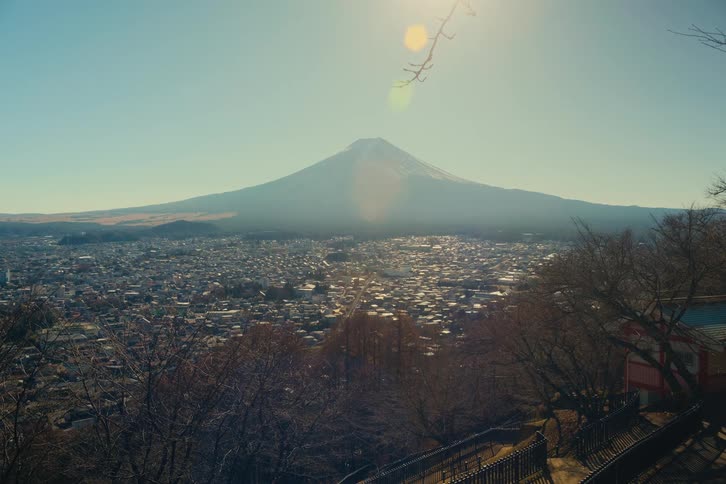 Mount fuji rises in the background above an urban area viewed from an elevated vantage point under a clear sky