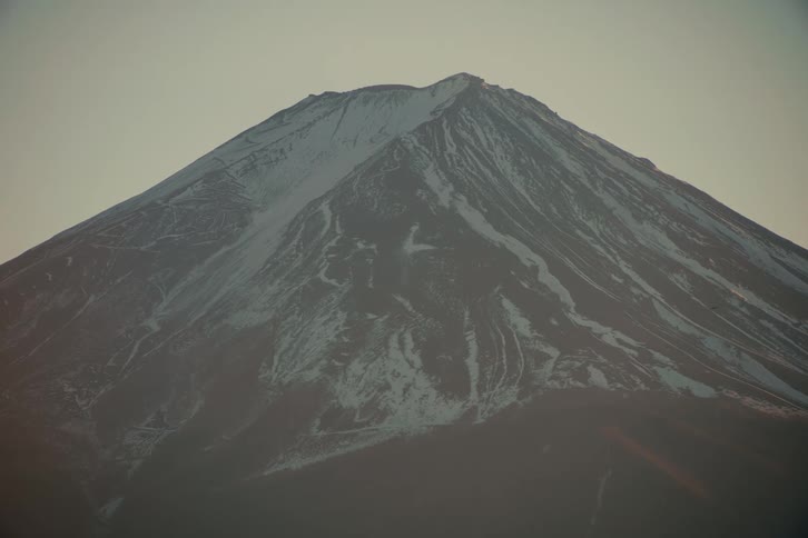 Snow on the rough terrain of a mountain under a hazy sky