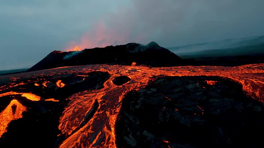Active volcanic eruption with glowing lava flow and dark sky in the background