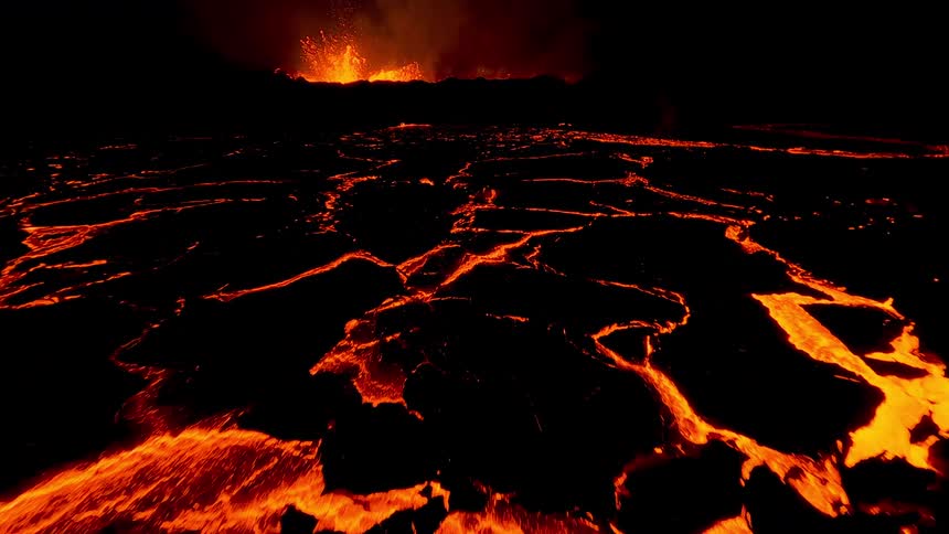 Molten lava glows in the darkness as it flows from an erupting volcano