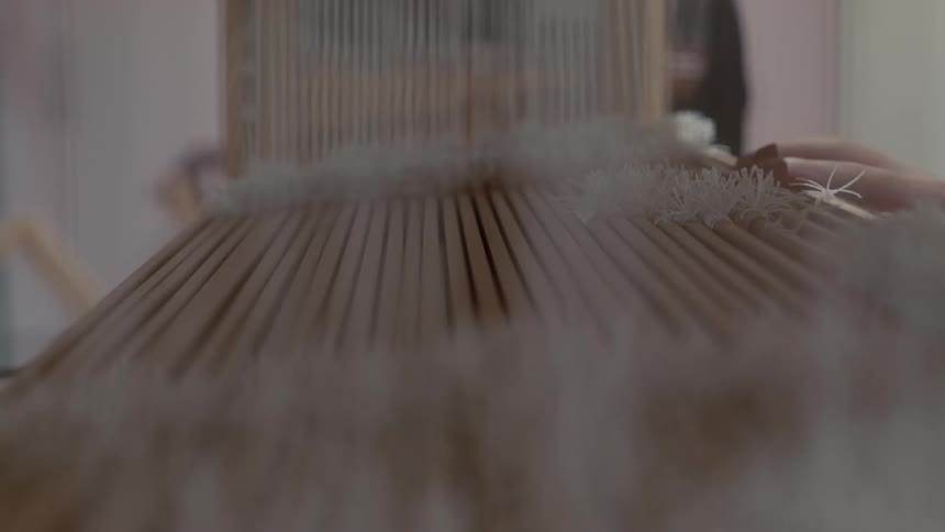 Female weaver weaves on a floor loom