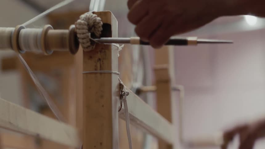An employee moving yarn on a wheel