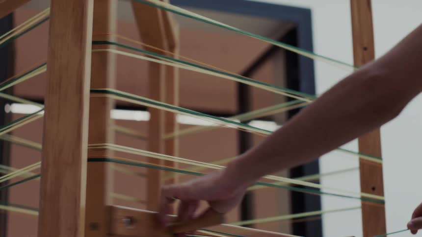 Tensioned threads run across a wooden frame during preparation of a handmade loom