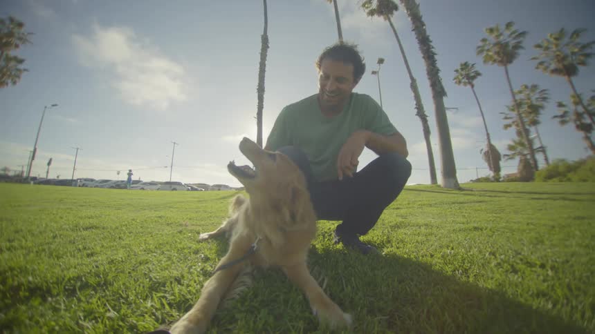 The man smiles while petting his dog