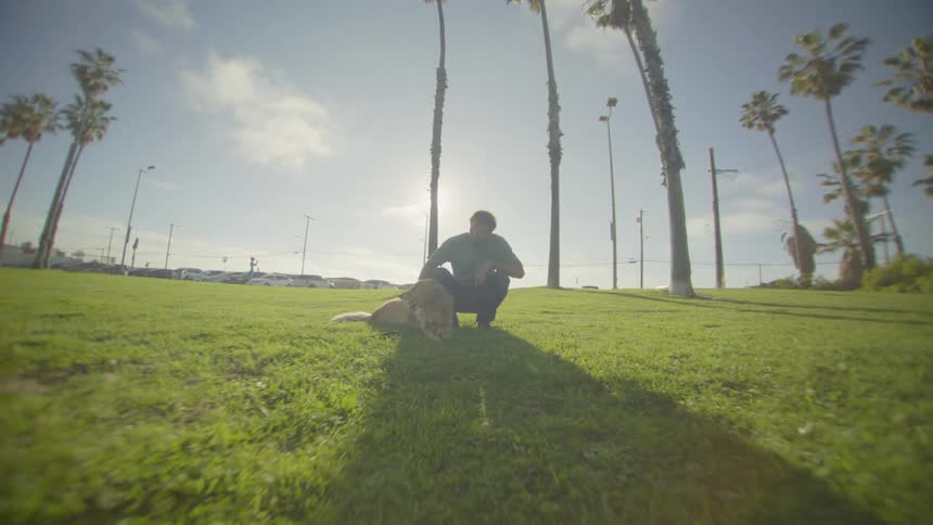The man is crouching and petting his dog