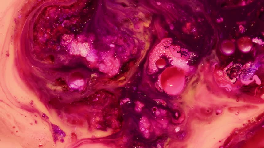Vibrant pink and purple liquids swirl together with glitter and bubbles